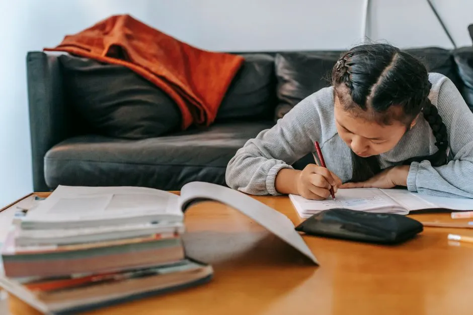 A child writing notes at a desk while working through a practice paper, illustrative photo